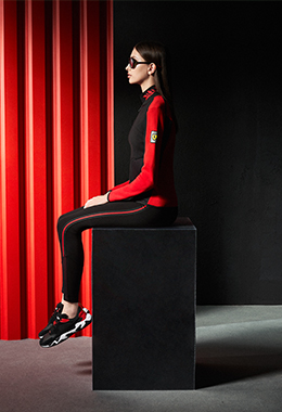 A three-quarter seated whole-body woman wears polo shirt in technical piqué with zip and laurel embroidery.