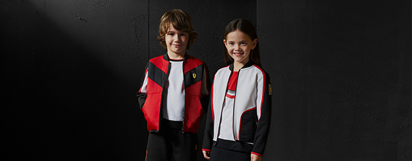 Two kids, male and female, wear Scuderia Ferrari's clothes and accessories.