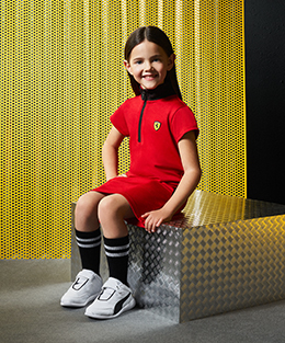 A seated girl wearing Scuderia Ferrari Mini-me clothes and accessories.