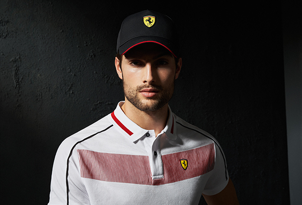 CLOSE UP OF A MAN WEARING A WHITE COTTON PIQUÉ POLO SHIRT WITH CONTRASTING INSERTS AND A BLACK CAP WITH FERRARI SHIELD