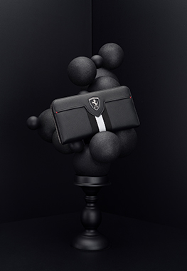 BLACK AND WHITE EVO LIVERY WALLET WITH ALL-AROUND ZIP CLOSURE PLACED ON A COMPOSITION OF BLACK CHRISTMAS BAUBLES.