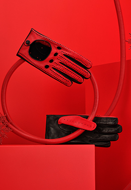Men's red driving gloves in lambskin nappa leather placed on a red tube.