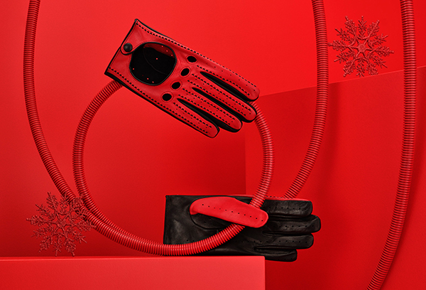 Men's red driving gloves in lambskin nappa leather placed on a red tube.