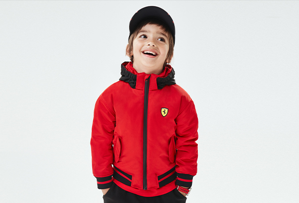 A SMILING BOY WEARING RED AND BLACK BOMBER JACKET IN RECYCLED PADDED SATIN WITH THERMO TECH