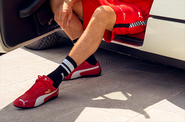 FOCUS ON A MAN'S LEGS WITH RED PUMA SCUDERIA FERRARI SPEEDCAT SHOES.