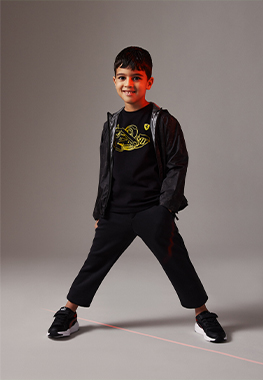 FULL-LENGTH PICTURE OF A BOY WEARING BLACK JACKET WITH ALL-OVER FERRARI SHIELD PRINT.