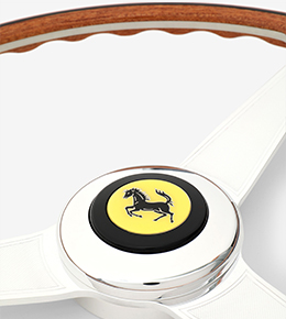 Two images of white steering wheel with Ferrari logo.