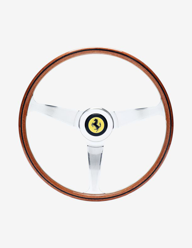 Two images of white steering wheel with Ferrari logo.