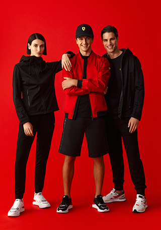 FULL-LENGTH PICTURE OF TWO MEN AND A WOMAN WEARING SCUDERIA FERRARI CLOTHES AND ACCESSORIES.
