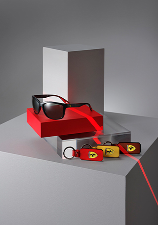 Ray-Ban for Scuderia Ferrari sunglasses with purple silver mirrored polarised lenses and red, yellow and brown natural leather keyrings with enamel Shield on red and grey geometric blocks.