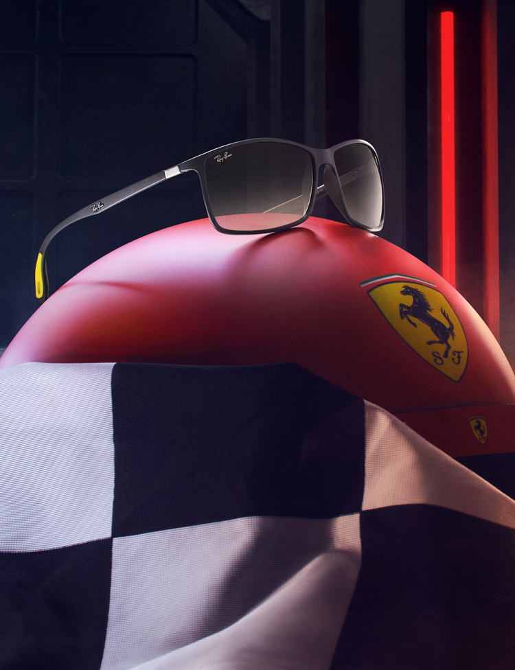 A man seen from behind standing in front of a vehicle under construction inside Maranello Car Factory in a red light