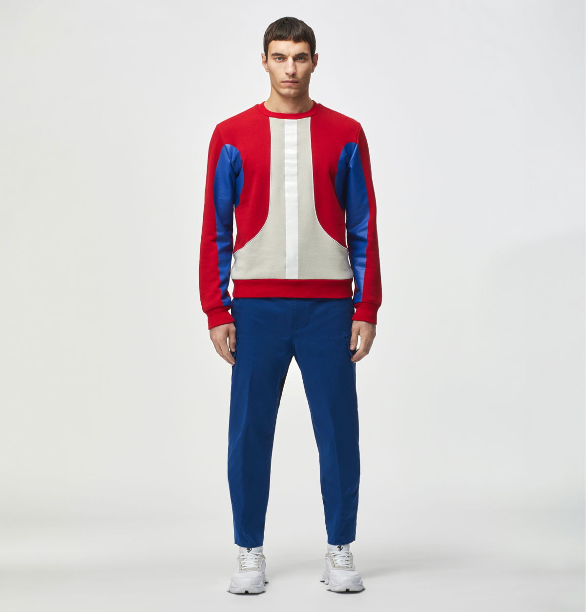 Model wearing a red jumper with blue trousers and white sneakers