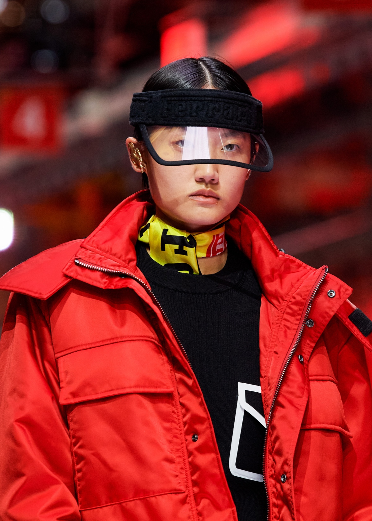 Model wearing black visor and red parka