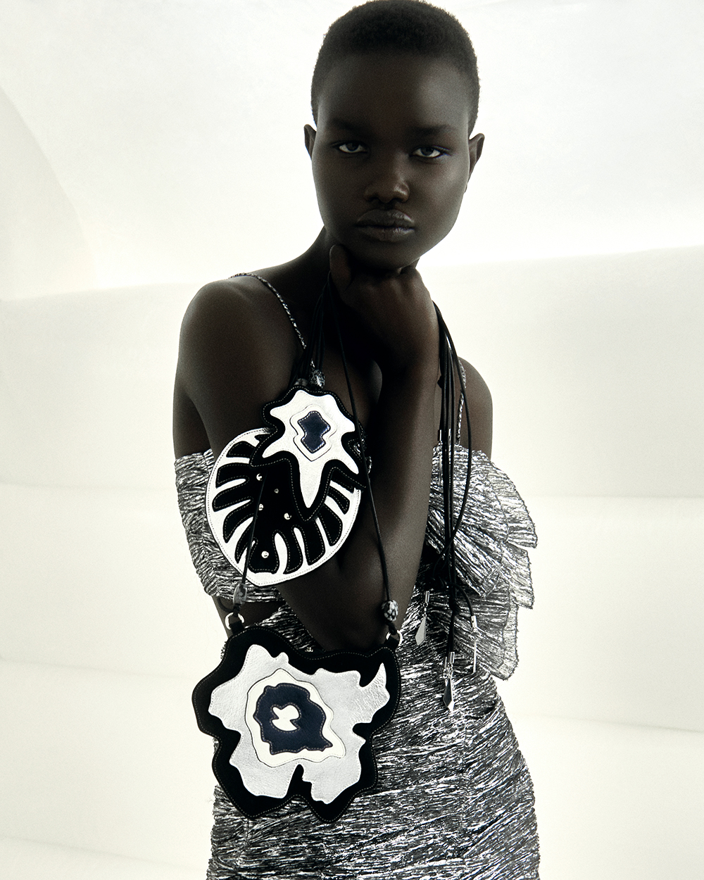 The model is wearing the Tikyna dress with the Monstera bag charm, the Arce bag charm and the Biskoo mini bag.