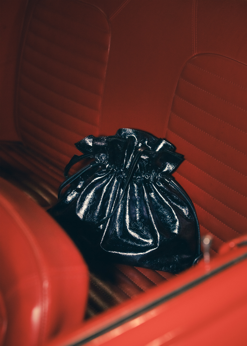 Photo of the black Ailey bag on a red vintage car seat